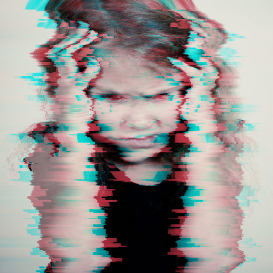 Portrait of sad blond little girl sitting outdoors near a  wall  at the day time. Concept of sadness. Glitched style photo.